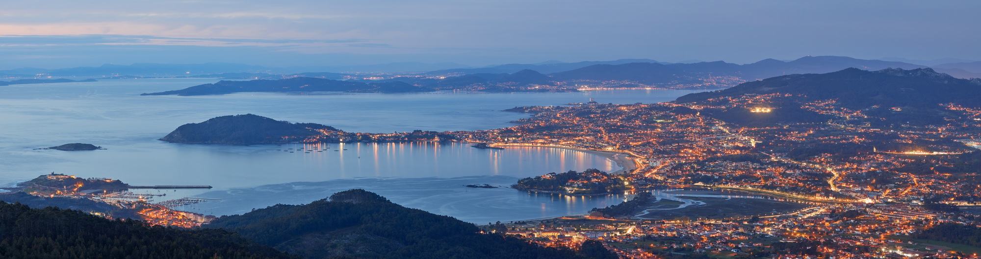 Panoramic of a beautiful sunset in the city with lights - Vigo estuary, Galicia, Spain.